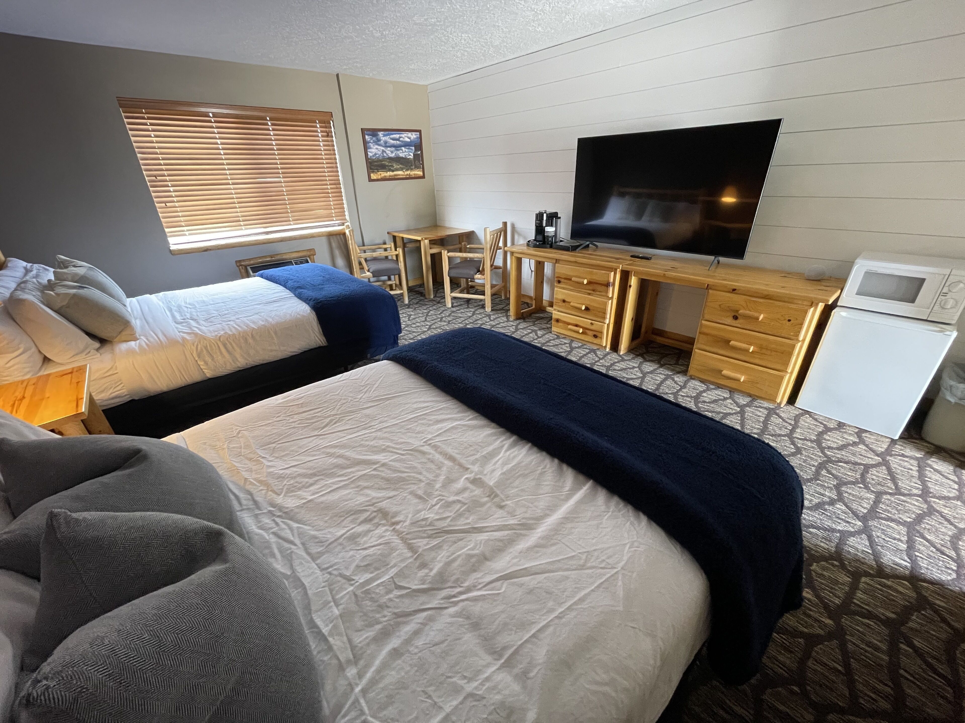 A hotel room with two beds, a desk, a television, and a microwave.