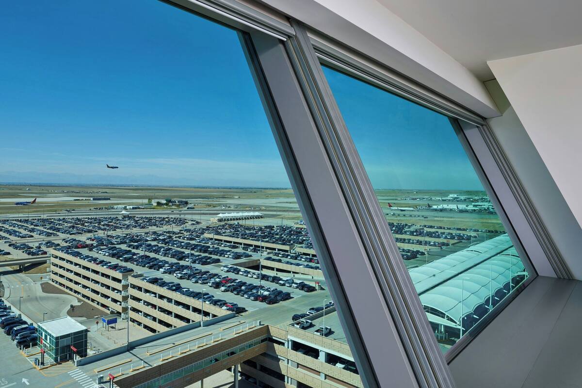 A view from a high-rise window overlooking a parking garage and airport.