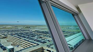 A view from a high-rise window overlooking a parking garage and airport.