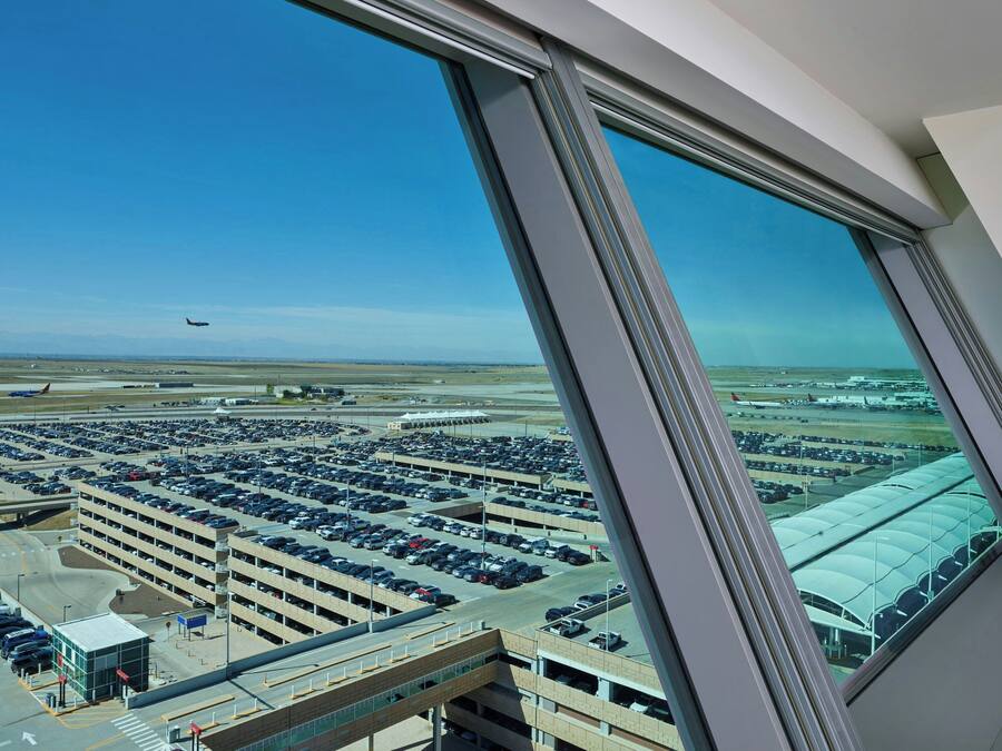 A view from a high-rise window overlooking a parking garage and airport.