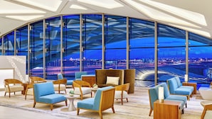 A modern lounge area with seating and a large window offering a view of a cityscape.