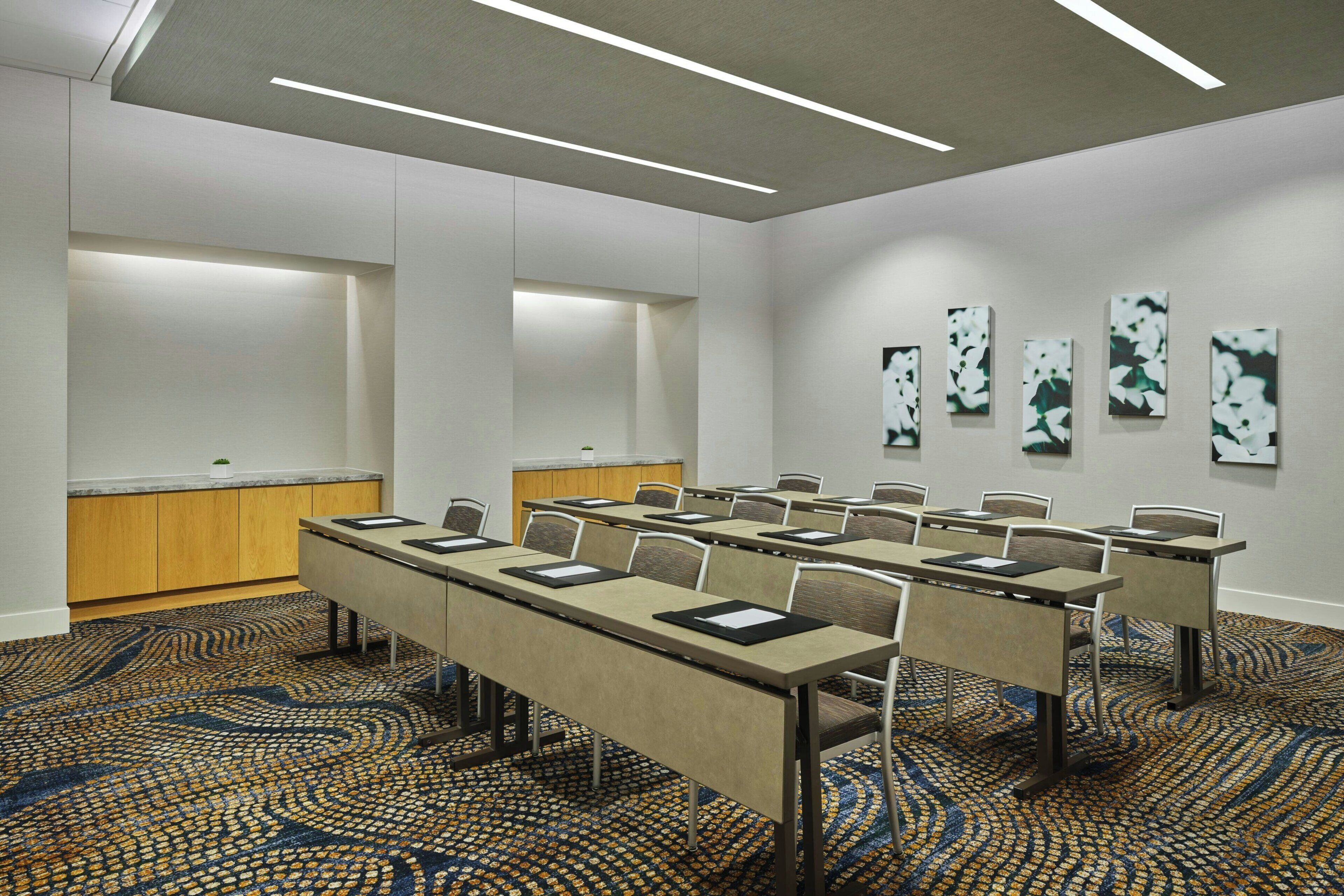 Une salle de conférence avec une longue table, des chaises, un pupitre et une moquette à motifs.