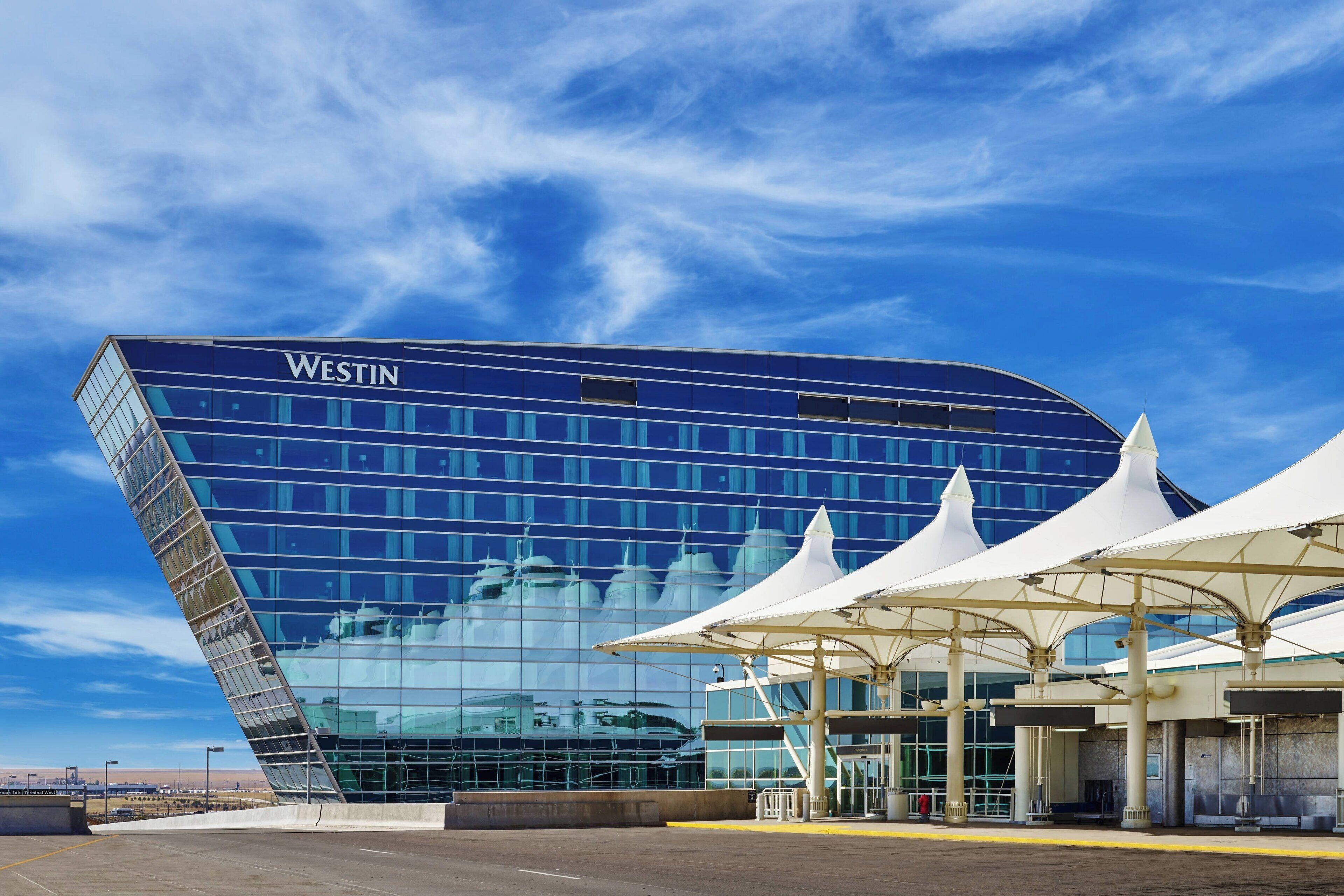 A modern hotel with a curved facade, large windows, and a covered entrance area.