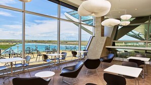 A modern dining area with large windows, contemporary chairs, and hanging pendant lights.