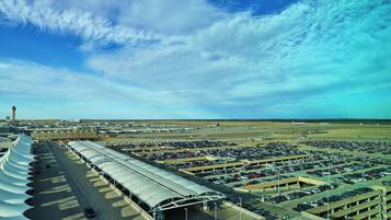 An airport terminal with multiple levels of parking, a clear sky, and a distant view of an airplane on the runway.
