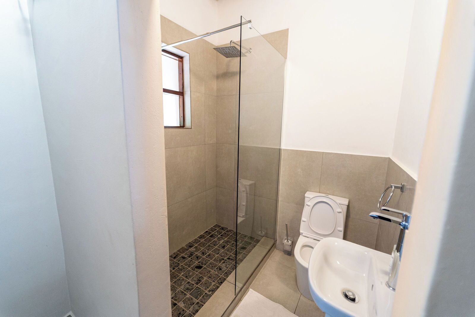 A small bathroom with a shower, toilet, and sink.