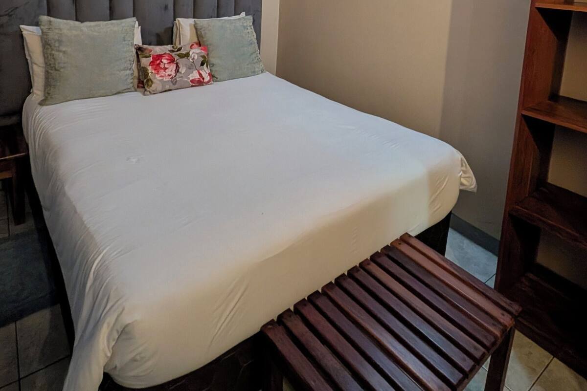 Ein Schlafzimmer mit einem Bett, einer hölzernen Bank, einem Kopfteil und einem Regal.