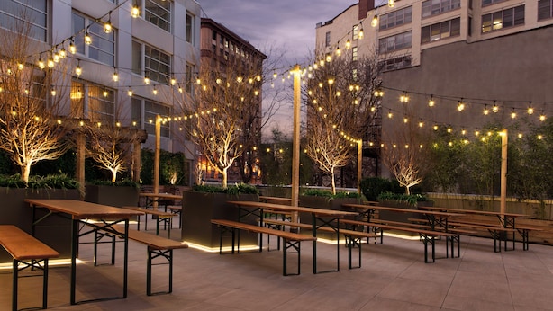An outdoor seating area with wooden benches and string lights.