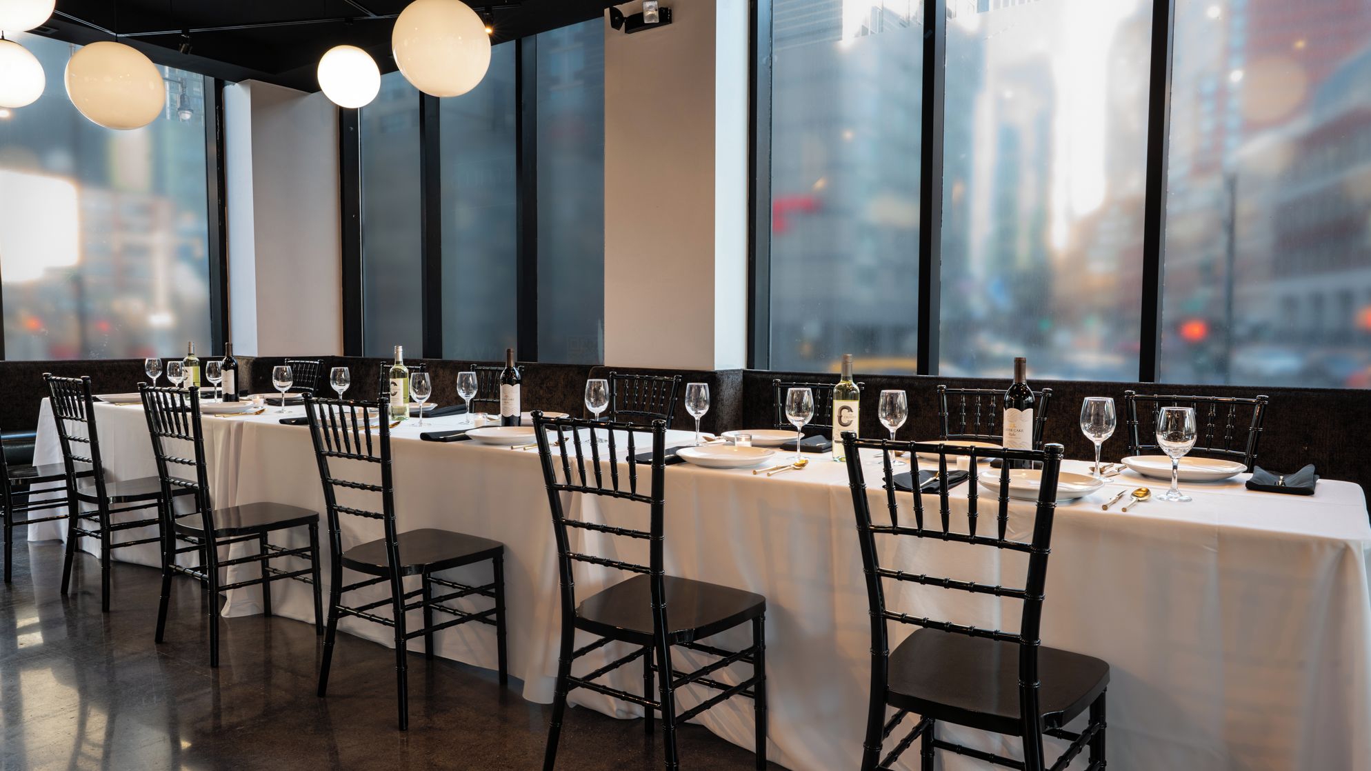 Un restaurante con mesas dispuestas para comer, sillas y botellas de vino.
