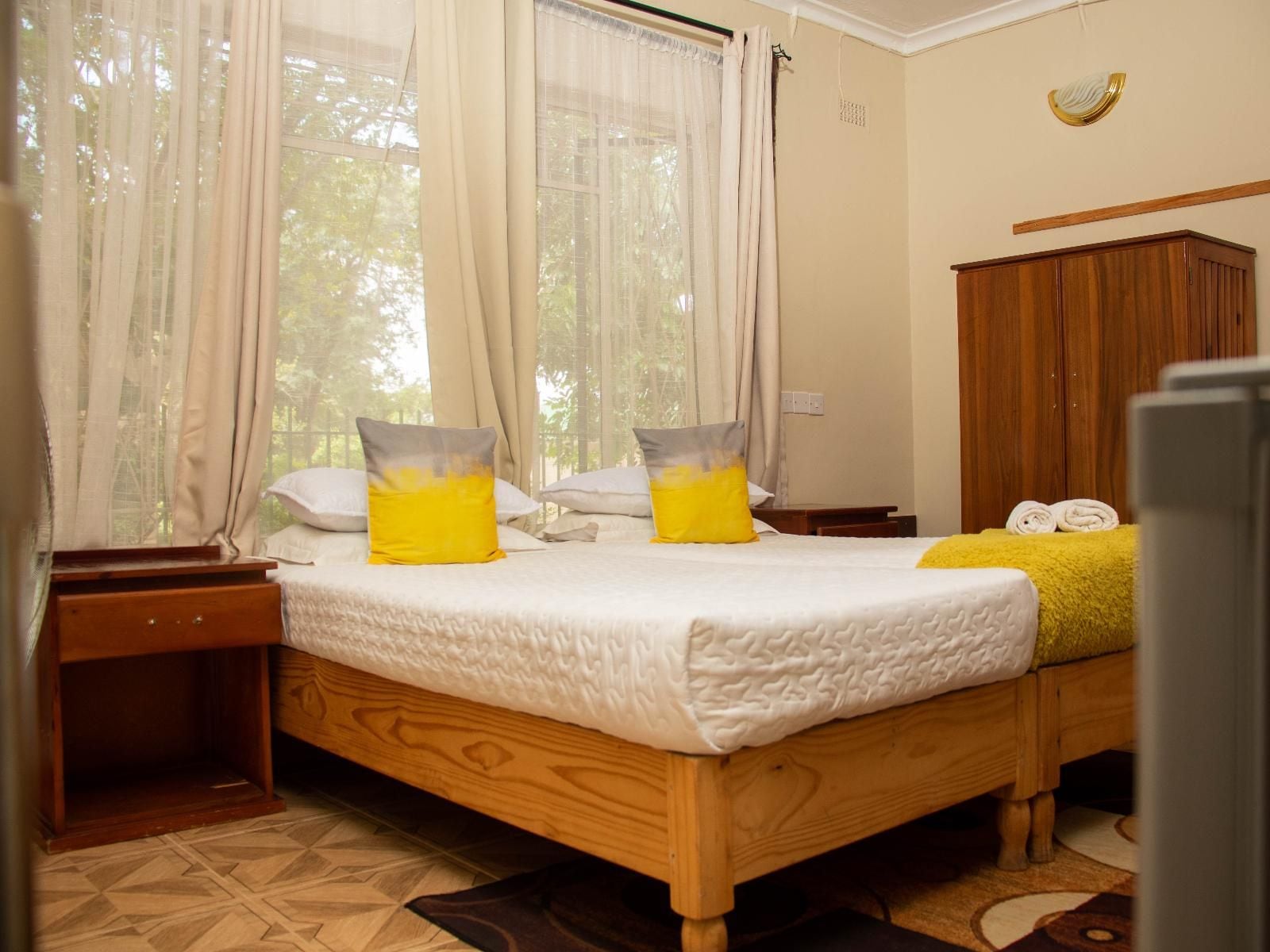 Quarto com cama de madeira, duas mesas de cabeceira, guarda-roupa e janela com cortinas.