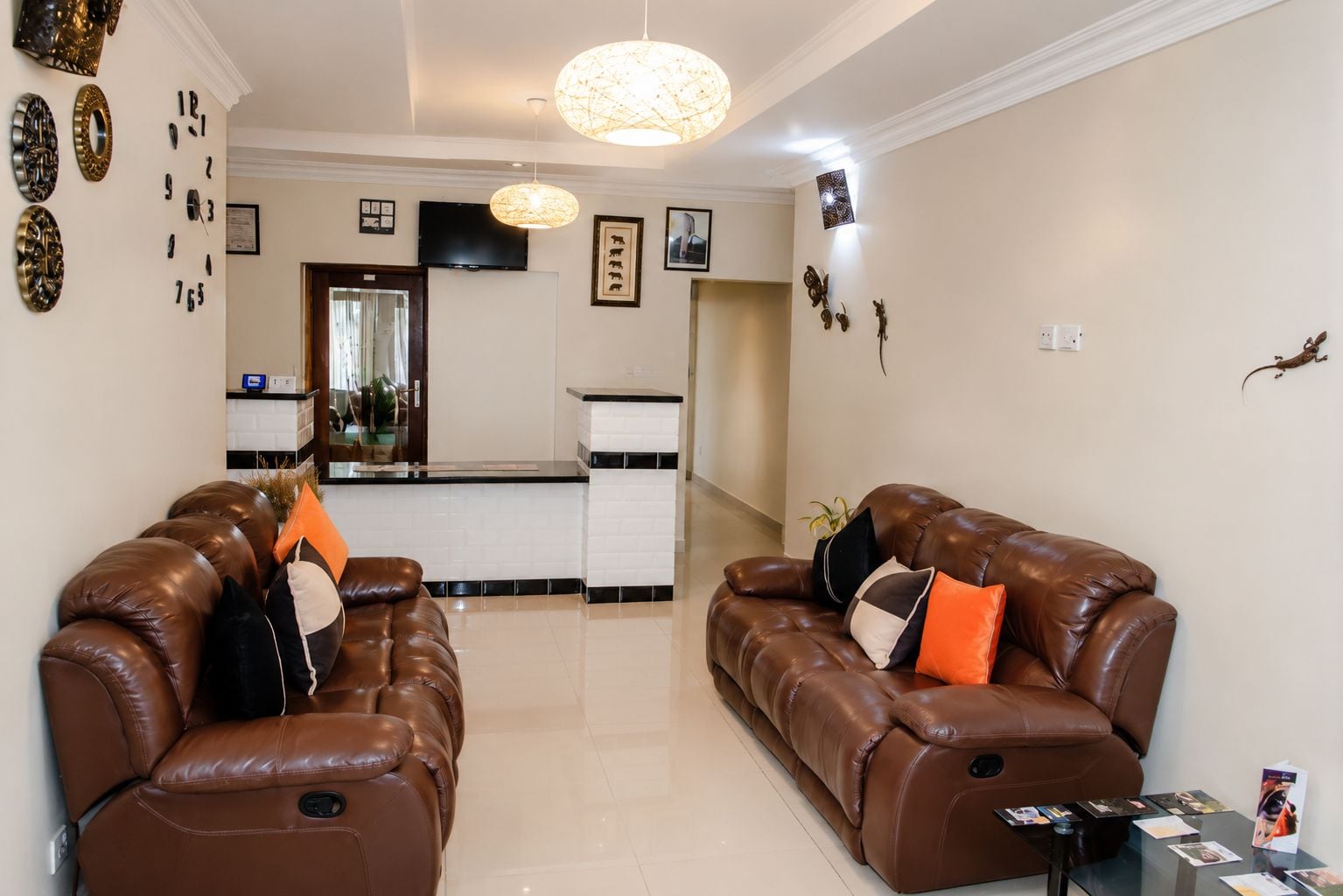 A living room with two brown leather sofas, a coffee table, and a kitchen area in the background.