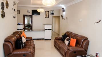 A living room with two brown leather sofas, a coffee table, and a kitchen area in the background.