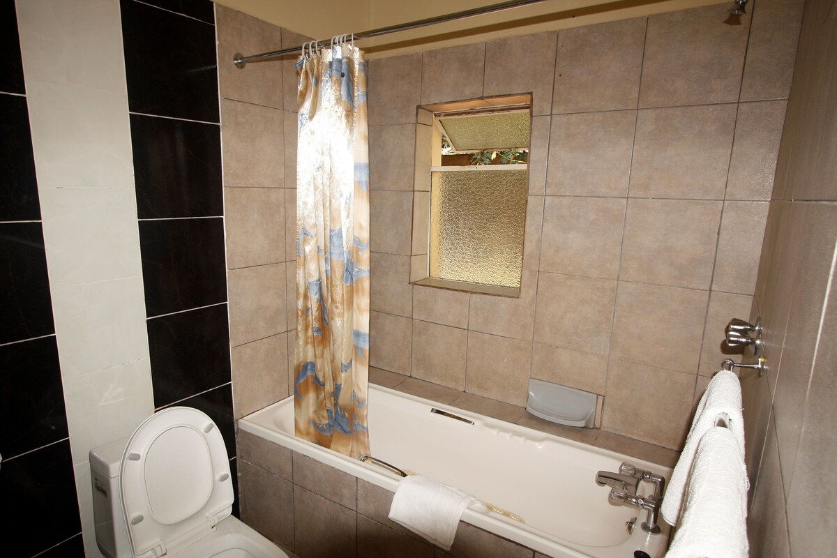 A bathroom with a toilet, bathtub, and shower curtain.