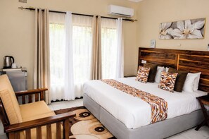 A hotel room with a bed, a chair, a coffee maker, and curtains.
