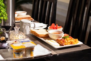 A breakfast table with toast, a bowl of soup, a pitcher, a bottle of juice, and a plate of eggs and potatoes. - Wild Trekkers Lodge (Victoria Falls)