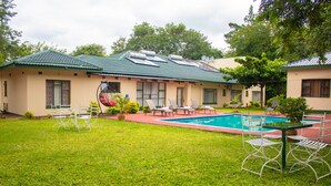 A house with a swimming pool, outdoor seating, and a green roof. - Wild Trekkers Lodge (Victoria Falls)