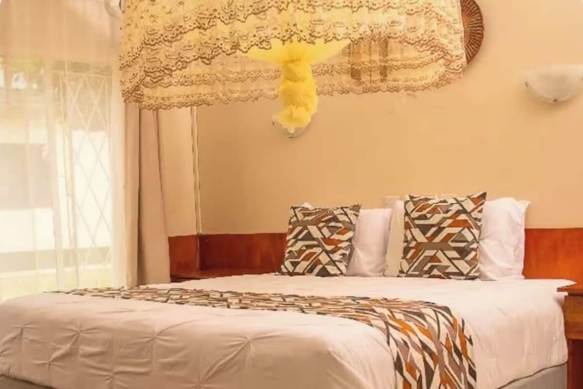 A bedroom with a large bed, a wooden headboard, and a decorative hanging.
