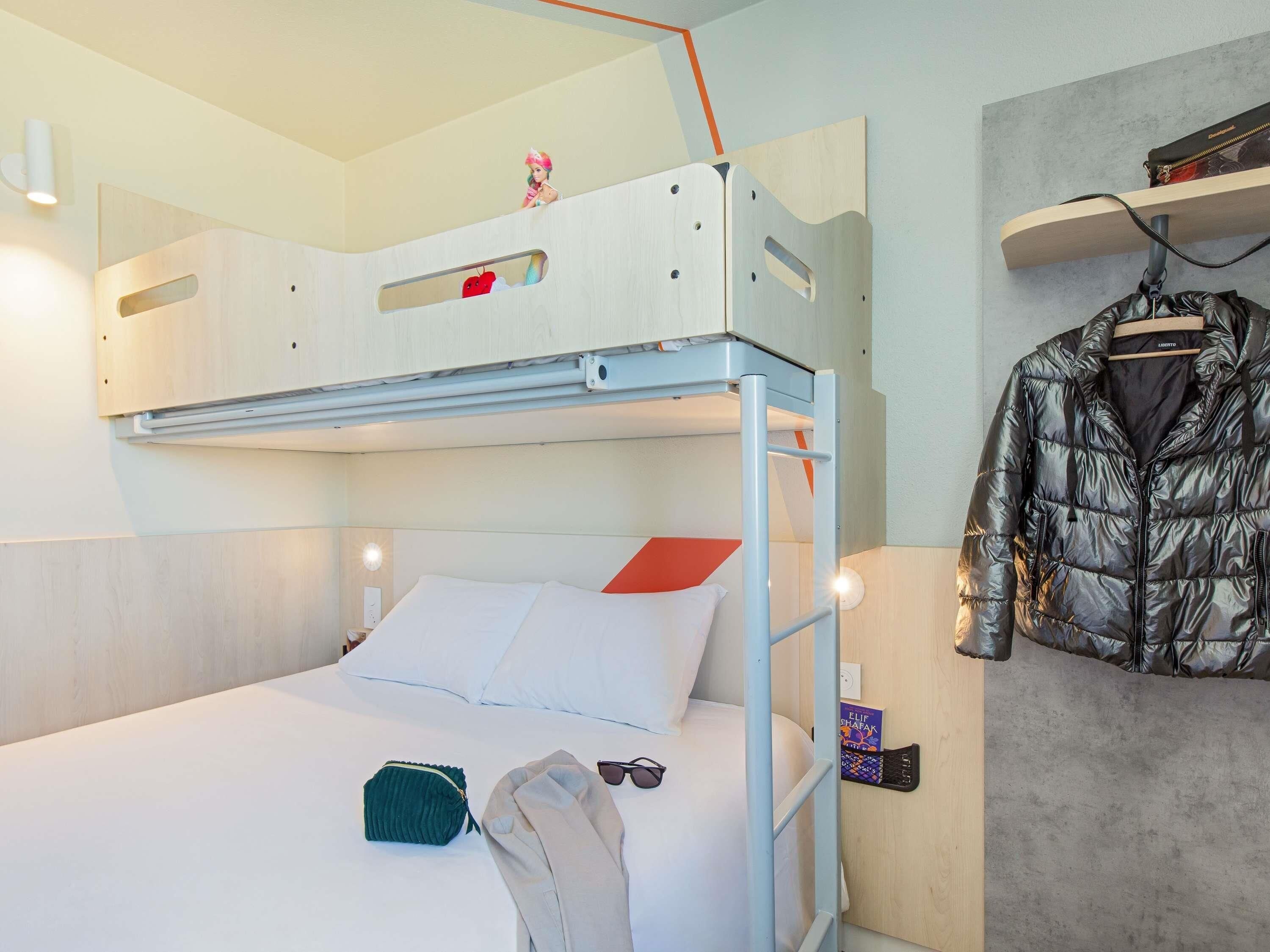 A bunk bed with a ladder, a small shelf, and a hanging jacket.