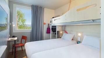 Quarto de hotel com duas camas, uma mesa, uma cadeira, janela com cortinas e vista para o exterior.