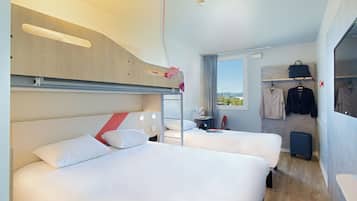 Habitación de hotel con dos camas, un escritorio, una ventana con vistas, un perchero y una maleta.