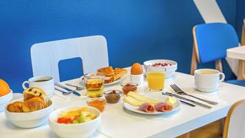 A breakfast table with croissants, eggs, fruit, and coffee.
