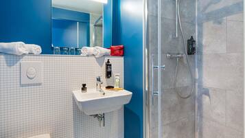 A modern bathroom with a glass shower enclosure, a white sink, and a mirror above it.