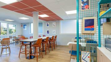 A conference room with a long table, multiple chairs, and a grid-patterned wall with artwork.