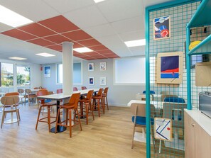 A conference room with a long table, multiple chairs, and a grid-patterned wall with artwork.