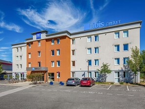Un hotel con estructura de dos pisos, estacionamiento y cielo azul despejado.