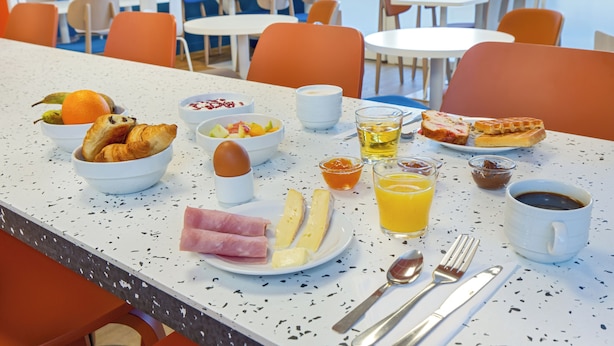 A breakfast table with croissants, eggs, cheese, ham, fruit, juice, and coffee. - ibis budget Valence Nord Plateau des Couleures (Saint-Marcel-les-Valence)