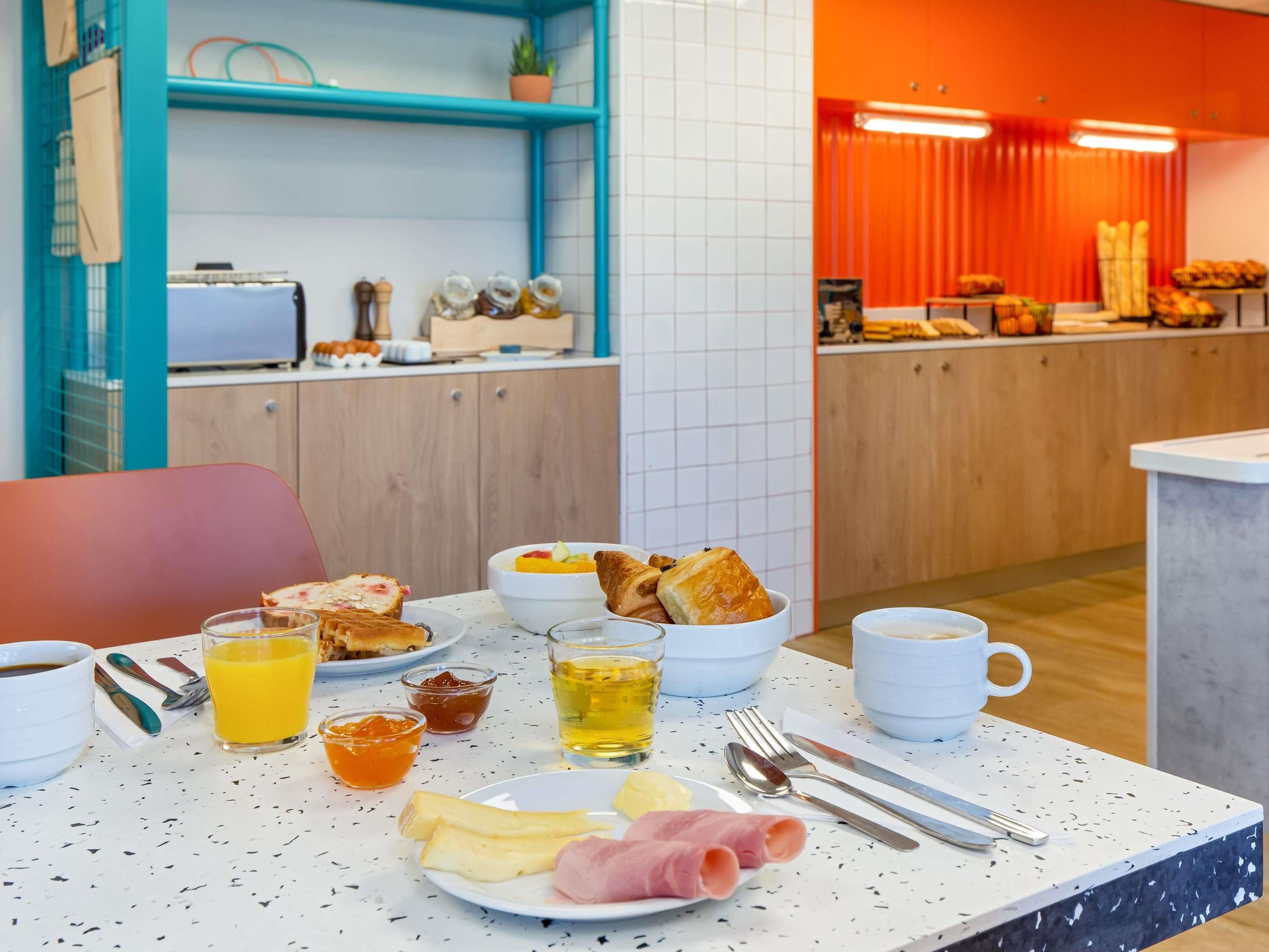 A breakfast setup with toast, eggs, ham, cheese, and beverages on a table.