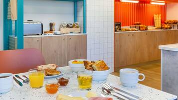 A breakfast setup with toast, eggs, ham, cheese, and beverages on a table.