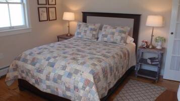 A bedroom with a large bed, two bedside tables with lamps, a small nightstand, and a door.