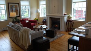 A living room with a fireplace, a sofa, a coffee table, and a dining area with a table set for two. - Butler House (Stowe)