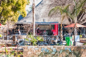 An outdoor dining area with stone walls, metal chairs, and a food truck.