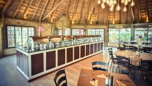 Un restaurante con una barra larga, techo de madera y luces colgantes.