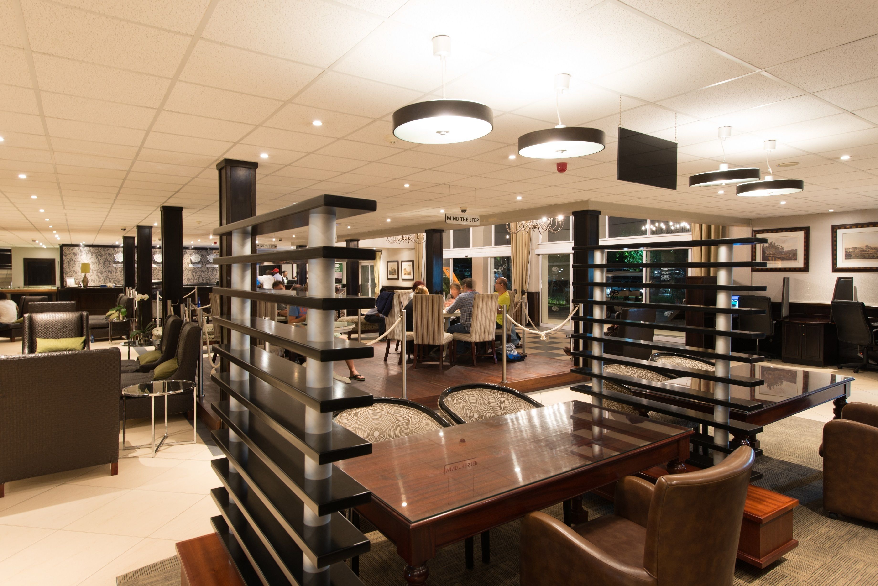 A modern furniture showroom with a large wooden table, several chairs, and a variety of sofas and armchairs.