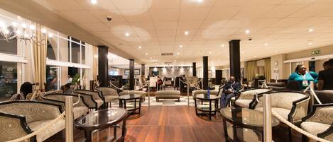A spacious lobby with multiple seating areas, a central staircase, and a view of the lobby area.