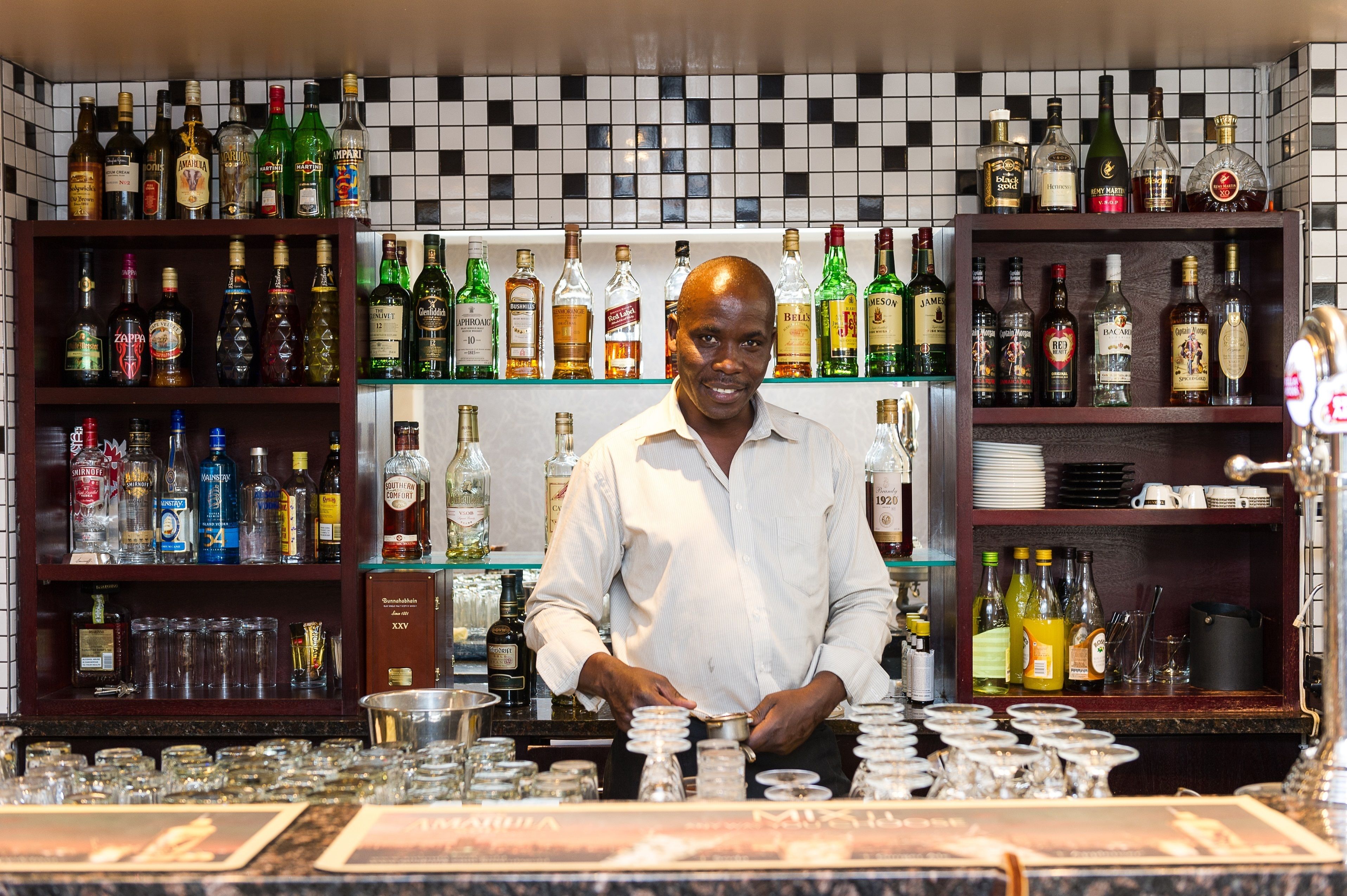 A bar with shelves of liquor bottles and glasses.