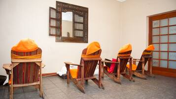 Four chairs with cushions sit in a row, accompanied by a large mirror and a small table.