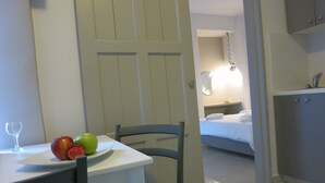 Ein Hotelzimmer mit einem Bett, einem Nachttisch mit Lampe sowie einer Essecke mit Tisch und Stühlen.