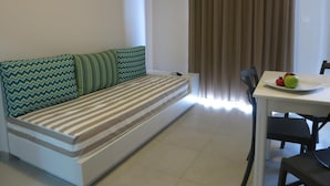 Ein modernes Wohnzimmer mit einer Couch, einem Esstisch mit Stühlen und einem Fenster mit Vorhängen.
