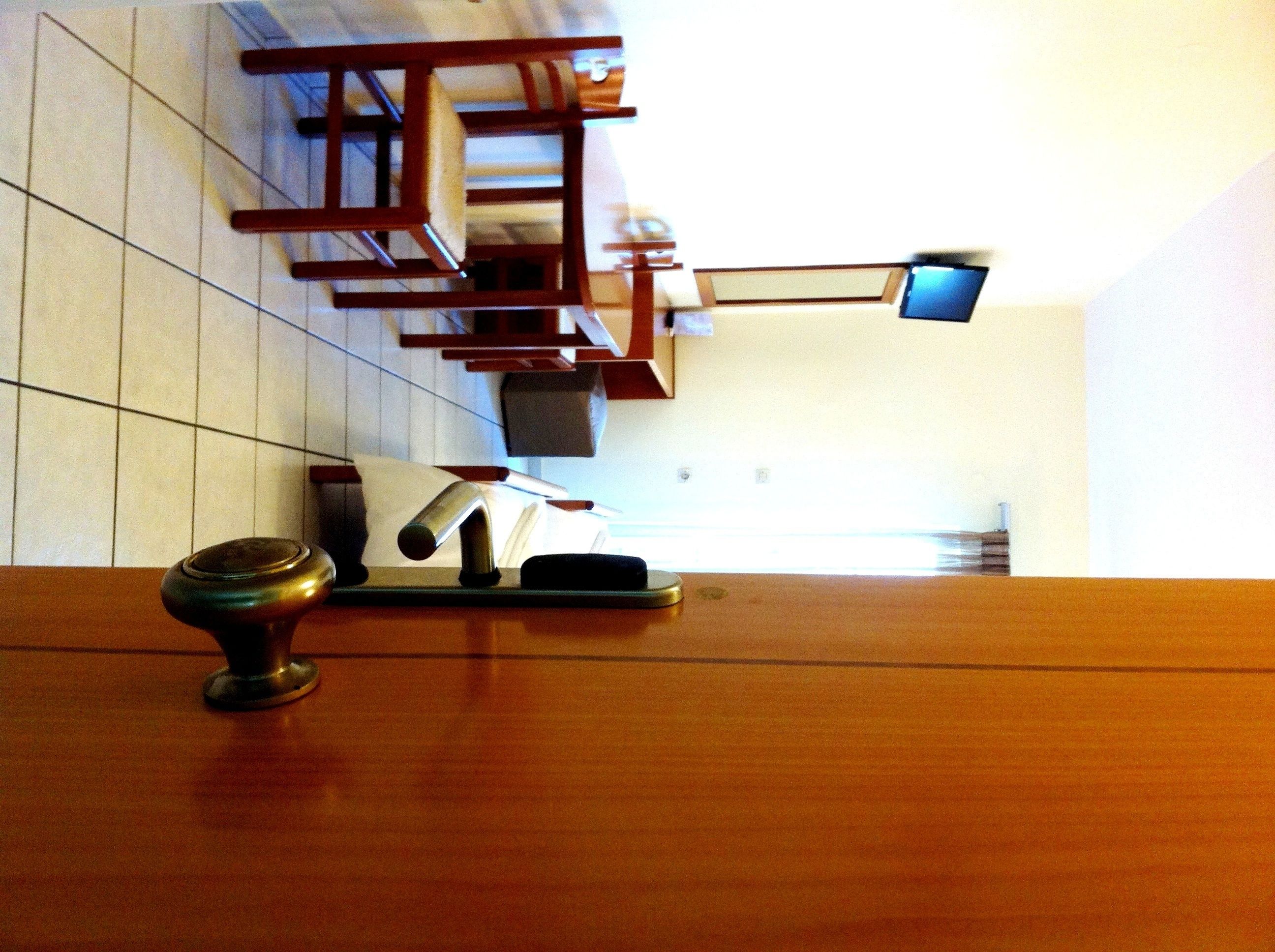 Et hotellobby med en træreception, en lille skrivebordslampe og et vægmonteret fjernsyn.