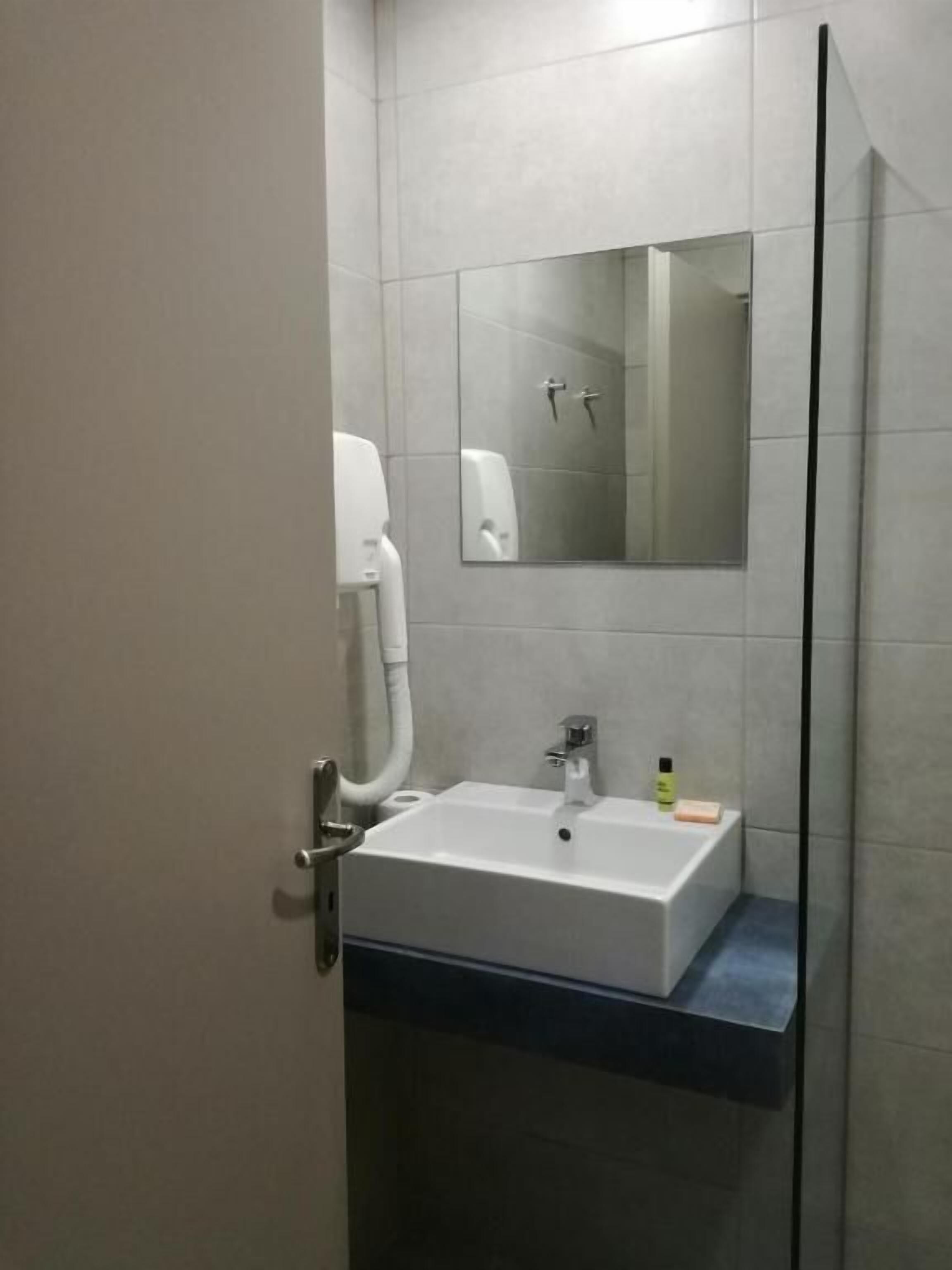 Ein Badezimmer mit einem weißen Waschbecken, einem Spiegel und einem Handtrockner.