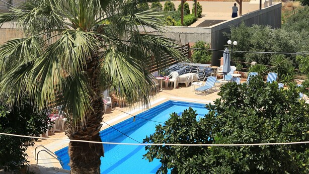 Zona residencial con piscina, palmeras y vista al mar.