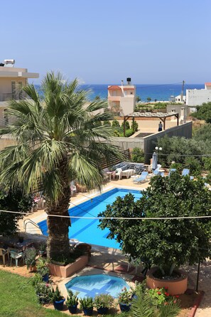 A residential area with a swimming pool, palm trees, and a view of the sea. - Maria Apartments (Hersonissos)