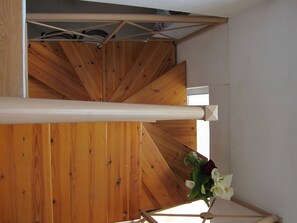 A wooden staircase with a white handrail and a flower arrangement at the top. - Baladinos Apartments  (Platanias)
