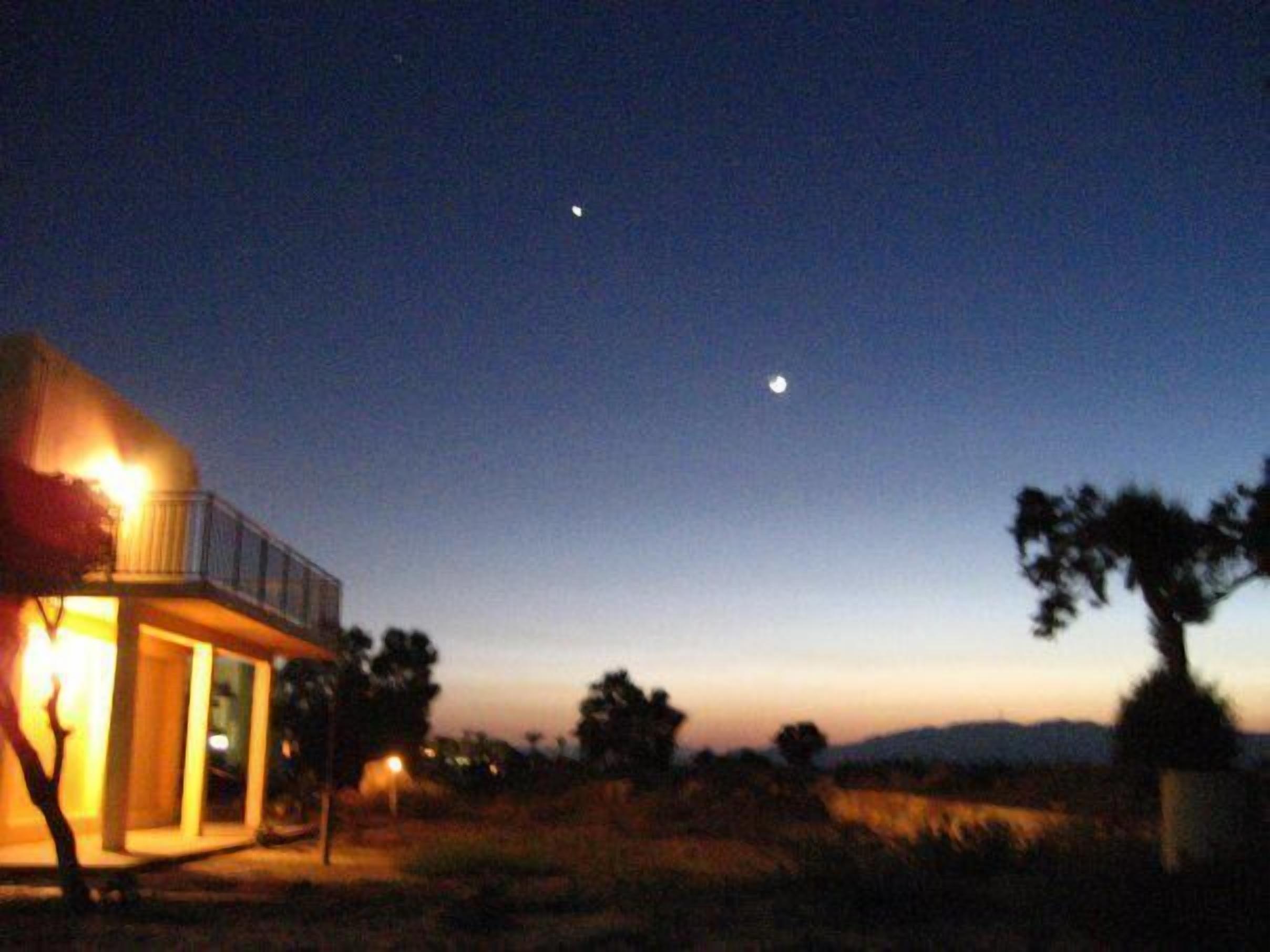 A house with a balcony and a moon in the sky.