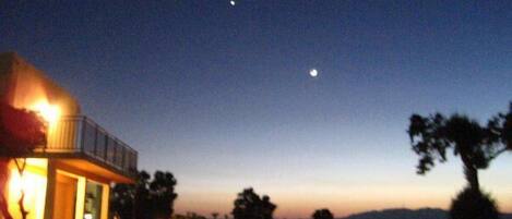 A house with a balcony and a moon in the sky.