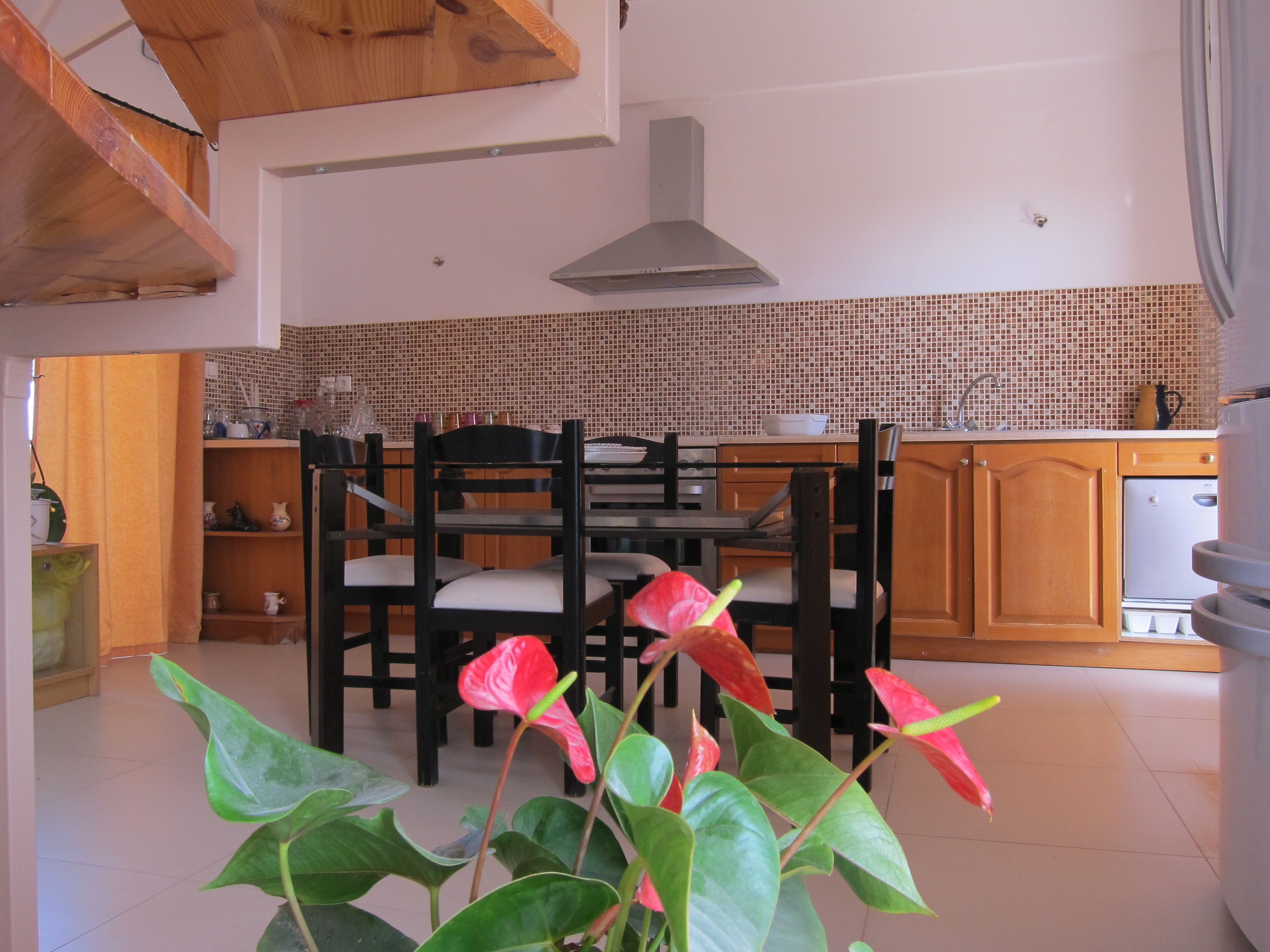 Una cocina con armarios de madera, salpicadero de azulejos y un comedor con sillas y mesa.